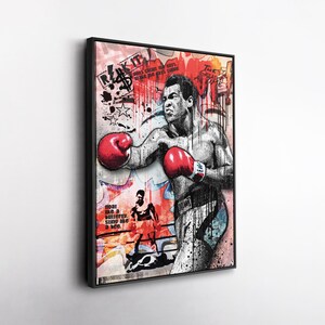 May include: A framed art print featuring a stylized illustration of a boxer in action, wearing red gloves. The artwork incorporates graffiti-style elements with text and splatters of red and black paint. The phrase "float like a butterfly, sting like a bee" is visible.