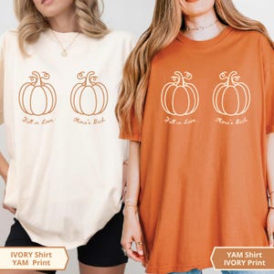 May include: Two short-sleeve crew neck t-shirts, one ivory and one burnt orange. Each shirt features two line-art pumpkin illustrations with the cursive text "Fall in Love" under the first pumpkin and "Olivia's Bach" under the second pumpkin.