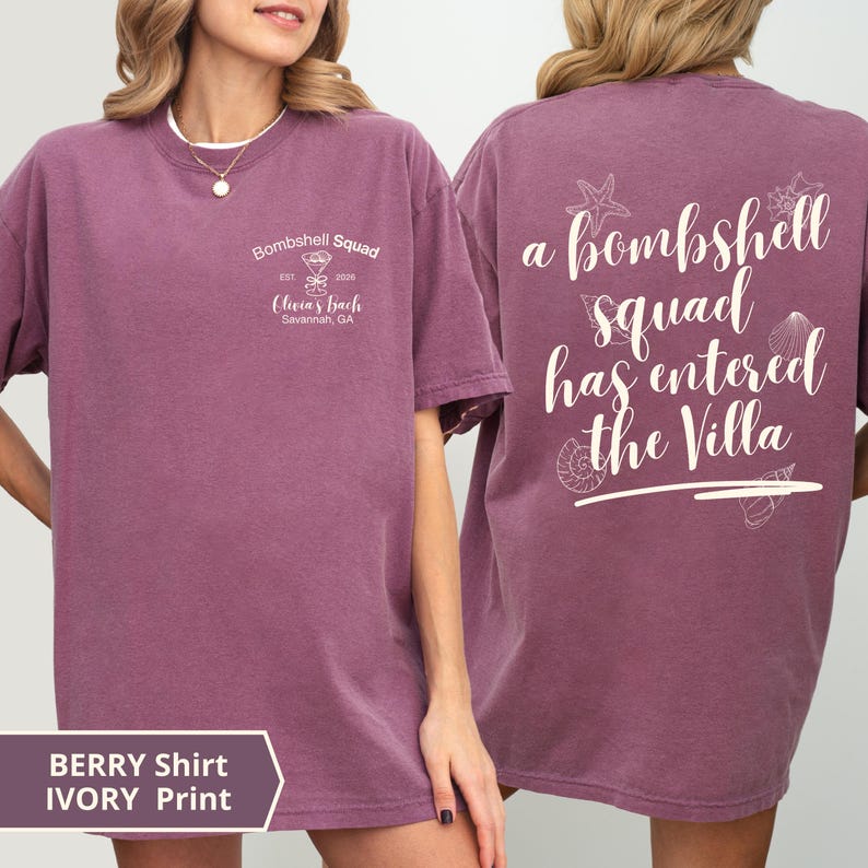 K&ouml;nnte beinhalten: Ein beerenfarbenes T-Shirt mit kurzen &Auml;rmeln und wei&szlig;em Siebdruck-Text sowie Grafiken. Die Vorderseite zeigt 'Bombshell Squad Est. 2026 Olivia's Bach Savannah, GA' mit einem Martiniglas. Auf der R&uuml;ckseite steht 'a bombshell squad has entered the Villa'.