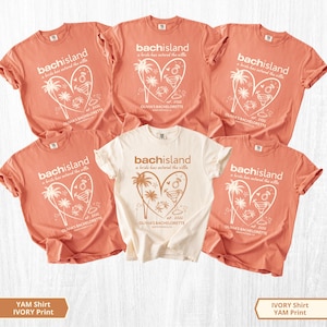 Puede incluir: Cinco camisetas de manga corta y cuello redondo en color coral y marfil. Cada camiseta presenta un gráfico de un corazón con palmeras, un cóctel, un cangrejo y un anillo, con el texto bachisland, a bride has entered the villa y Olivia's Bachelorette.