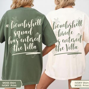 K&ouml;nnte beinhalten: Ein moosgr&uuml;nes T-Shirt mit wei&szlig;em Text a bombshell squad has entered the Villa und ein elfenbeinfarbenes T-Shirt mit moosgr&uuml;nem Text bombshell bride has entered the Villa, beide mit Strichzeichnungen von verschiedenen Muscheln.