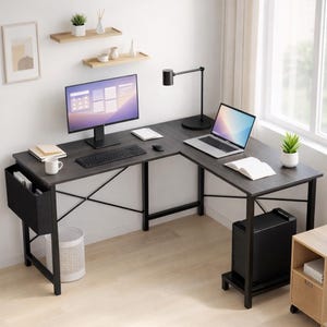 May include: An L-shaped gray desk with black metal legs, a computer monitor, keyboard, and laptop. A black desk lamp, a white mug, and a small plant are also on the desk. A black storage bin and a computer tower are visible.
