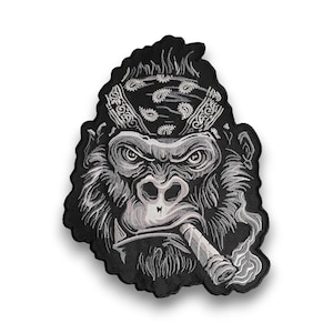 May include: Embroidered patch of a gorilla wearing a bandana and smoking a cigar. The gorilla is in black and white with detailed shading. The bandana has a paisley pattern. Smoke curls from the lit cigar.