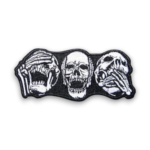 Puede incluir: Parche bordado en blanco y negro con tres calaveras. Una calavera se cubre los ojos, otra la boca y la tercera las orejas. El parche tiene un borde negro y está diseñado para ropa o accesorios.