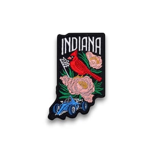 May include: Embroidered patch in the shape of Indiana, featuring a red cardinal, pink flowers, and a blue race car. The word "INDIANA" is embroidered in white block letters on a black background.