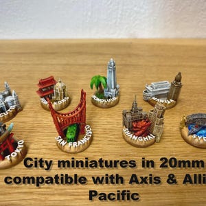 Peut inclure: Miniatures de villes, dont Tokyo et Sydney, sur une surface en bois. Les miniatures mesurent environ 20 mm et sont compatibles avec Axis & Allies Pacific. Le texte indique "City miniatures" et "Pacific".