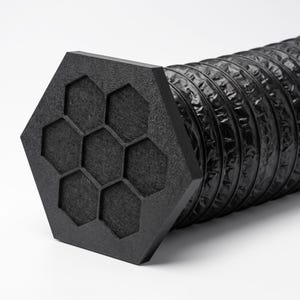 Può includere: Un tappo esagonale nero caratterizzato da un motivo a nido d'ape con sette intagli esagonali incassati, fissato a un tubo di ventilazione cilindrico nero, flessibile e nervato, con finitura opaca e superficie testurizzata a fisarmonica.