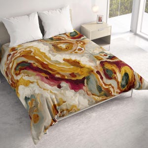 May include: A bed featuring a comforter with an abstract, swirling pattern in shades of mustard yellow, deep burgundy, cream, and muted teal. Two plain white pillows are positioned at the head of the bed, which is set within a bedroom space.