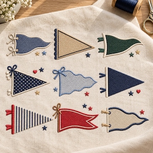 Puede incluir: Un diseño de bordado sobre tela beige claro que presenta nueve banderines de diversas formas y colores, incluyendo azul, rojo, verde y beige. Los banderines están decorados con rayas, lunares y pequeñas estrellas y corazones bordados.