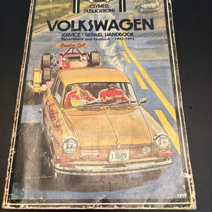 May include: A vintage Clymer Publications Volkswagen Service Repair Handbook for Squareback and Fastback models from 1962-1972. The cover features an illustration of a gold Volkswagen car on a road with two people inside and a race car trailer behind.