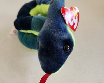 Pode incluir: Uma cobra de pelúcia verde e azul com uma língua vermelha e uma etiqueta Ty anexada. A cobra está enrolada em um círculo.