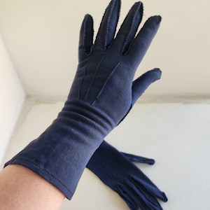 Pode incluir: Um par de luvas longas azul-marinho com um design sutil costurado. As luvas são feitas de um tecido macio e elástico e têm um visual clássico e elegante.