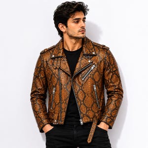 May include: A brown and black snakeskin-patterned motorcycle jacket featuring a notched lapel, silver-toned metal zippers on the front and pockets, shoulder epaulets, and an adjustable waist belt with a buckle, worn over a plain black shirt.