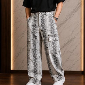 Puede incluir: Pantalones cargo de talle alto con estampado de piel de serpiente en gris y blanco. Estos pantalones de pernera ancha incluyen dos grandes bolsillos cargo laterales con solapa y un pequeño bolsillo horizontal con cremallera en el muslo izquierdo.