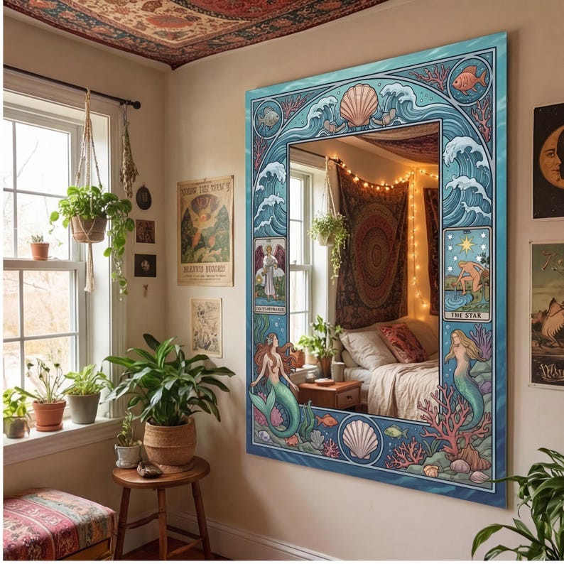 May include: A large, rectangular mirror with a blue frame featuring a mermaid and ocean-themed design. The mirror's frame includes illustrations of waves, seashells, and fish. The mirror reflects a bedroom with a bed, plants, and decorative tapestries.