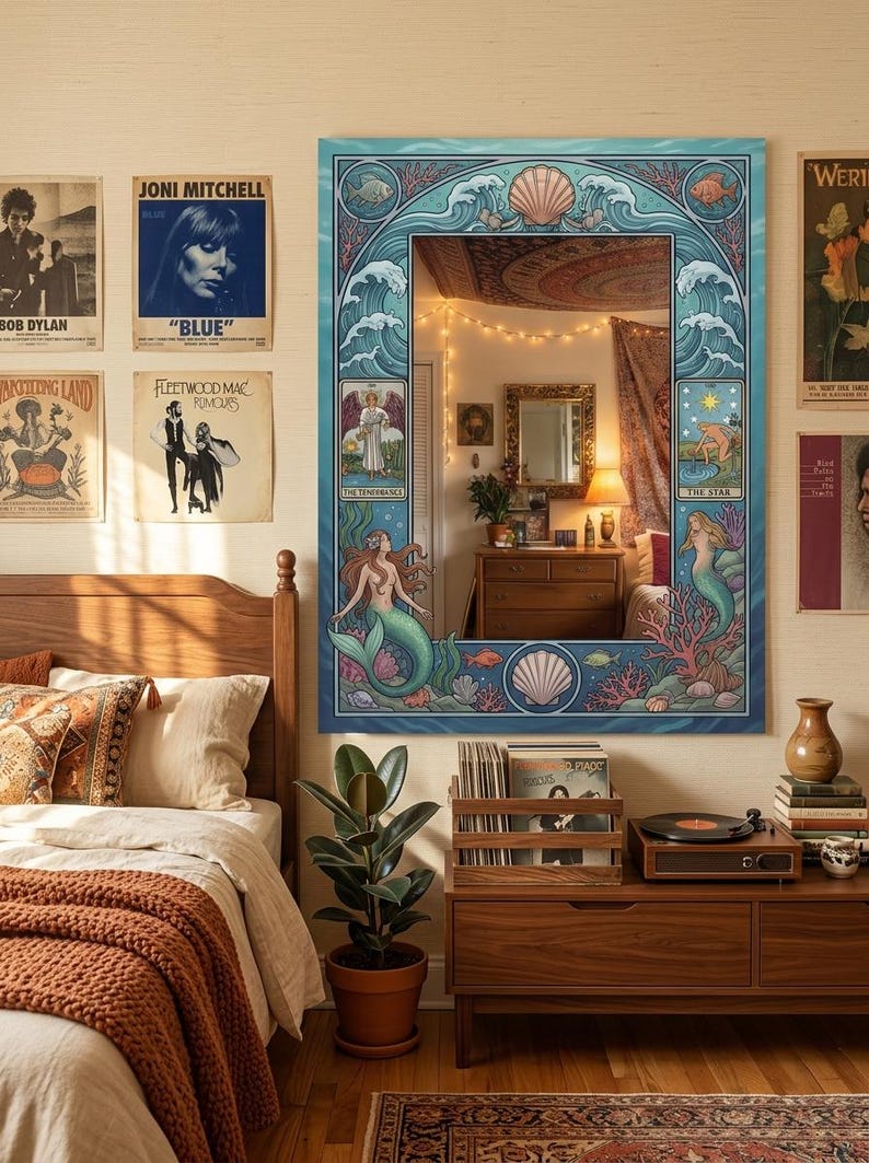 May include: A large, rectangular mirror with a blue, ocean-themed frame featuring mermaids, seashells, and waves. The mirror hangs above a wooden dresser, reflecting the room. Album covers and a record player are visible.