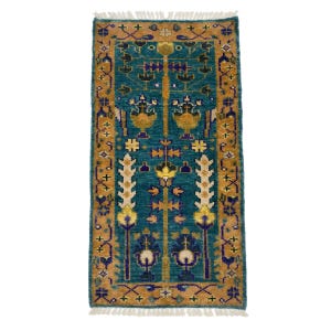 Könnte beinhalten: Ein rechteckiger, türkisfarbener Teppich mit einem aufwendigen Blumenmuster. Der Teppich hat einen Rand und ein zentrales Design in Gold-, Gelb- und Lilatönen. Er hat einen Fransenrand und eignet sich für einen Flur oder einen kleinen Raum. Misst ca. 120 cm x 60 cm.