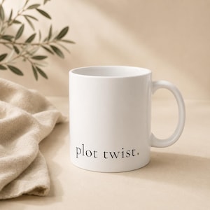 Pode incluir: Caneca de cerâmica branca com a frase "plot twist." impressa em preto. A caneca tem uma alça curva e está colocada sobre um fundo neutro com um pano macio e um galho frondoso.