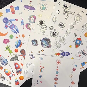 May include: A selection of temporary tattoos with space-themed illustrations. The sheets display colourful designs of astronauts, rockets, planets, stars, and aliens. Some designs are in colour, while others are black and white.
