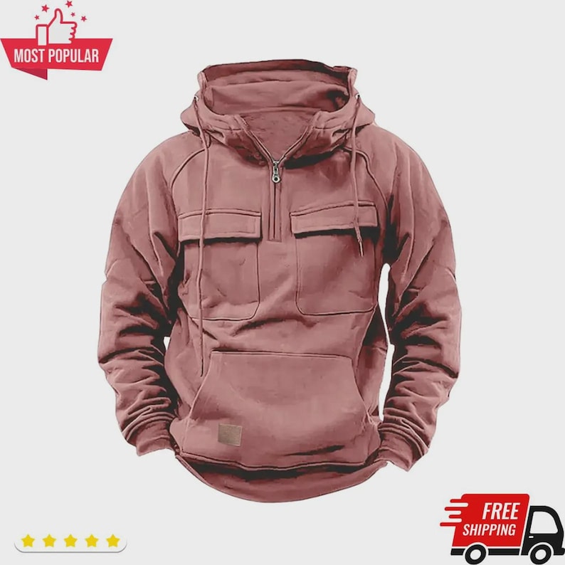 May include: A dusty rose-colored hooded sweatshirt with a half-zip closure, two front pockets, and a kangaroo pocket. The sweatshirt has a drawstring hood and a small rectangular patch near the bottom. The words "MOST POPULAR" are in a red banner.