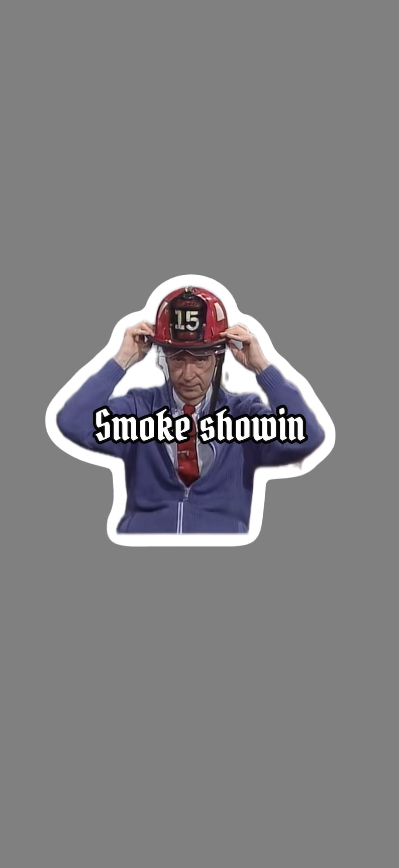 May include: A sticker featuring a person wearing a red firefighter helmet with the number 15 on it, a blue zip-up sweater, and a red tie. The text "Smoke showin" is written in a stylized font.