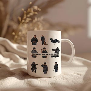Könnte beinhalten: Weißer Keramikbecher mit Illustrationen von Polizisten in verschiedenen Posen. Der Becher trägt den deutschen Text "EINSATZBEREIT NACH DEM ERSTEN KAFFEE", was übersetzt "Bereit nach dem ersten Kaffee" bedeutet.