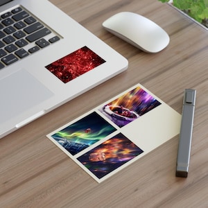 May include: A laptop with a red and black sticker featuring a nebula design. A white mouse and a postcard with four colorful space-themed images are on a wooden surface. A gray marker is also present.