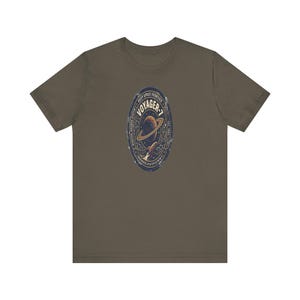 May include: Olive green t-shirt featuring a distressed oval graphic with the text "VOYAGER-7" and a depiction of a planet with rings and a rocket. The graphic is in shades of blue, gold, and brown.