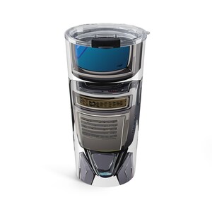 May include: A tall, clear travel tumbler with a black lid and a futuristic design. The tumbler features a detailed, metallic gray and black graphic with a blue interior visible through the clear top.