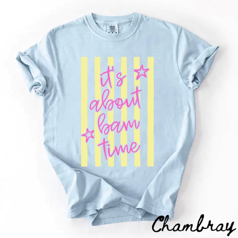 May include: Pale blue t-shirt featuring yellow vertical stripes and the pink text "It's about bam time". Two pink stars are on either side of the text. The word "Chambray" is written in black script at the bottom.
