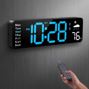 May include: Black digital wall clock displaying the time as 10:28 PM in bright blue digits. The clock also shows the day of the week, weather icons, and the temperature as 76°F. A remote control is held nearby.