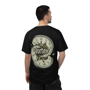 Op de afbeelding: Zwart T-shirt met een crèmekleurig klokontwerp en het woord "Vortex". Het klokontwerp heeft tandwielen en Romeinse cijfers. Het T-shirt heeft korte mouwen.