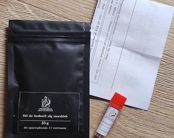 Puede incluir: Una bolsa negra etiquetada Sól do hodowli alg morskich 35 g, un pequeño vial transparente con tapa roja etiquetado Guillard F y una hoja de instrucciones blanca titulada Preparing the medium, que detalla los pasos para 1 litro de agua.