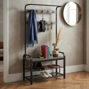May include: A black metal hall tree with a gray wood-look bench and two lower wire shelves. The unit features a top hanging rod, multiple hooks holding a blue scarf and black gloves, and a surface displaying books, a vase, and a coiled leather belt.