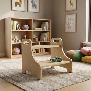 May include: A light-colored wooden step stool with two steps and handle cutouts. A small green toy car sits on the top step. The stool is in a room with a bookshelf, toys, and colorful pillows.