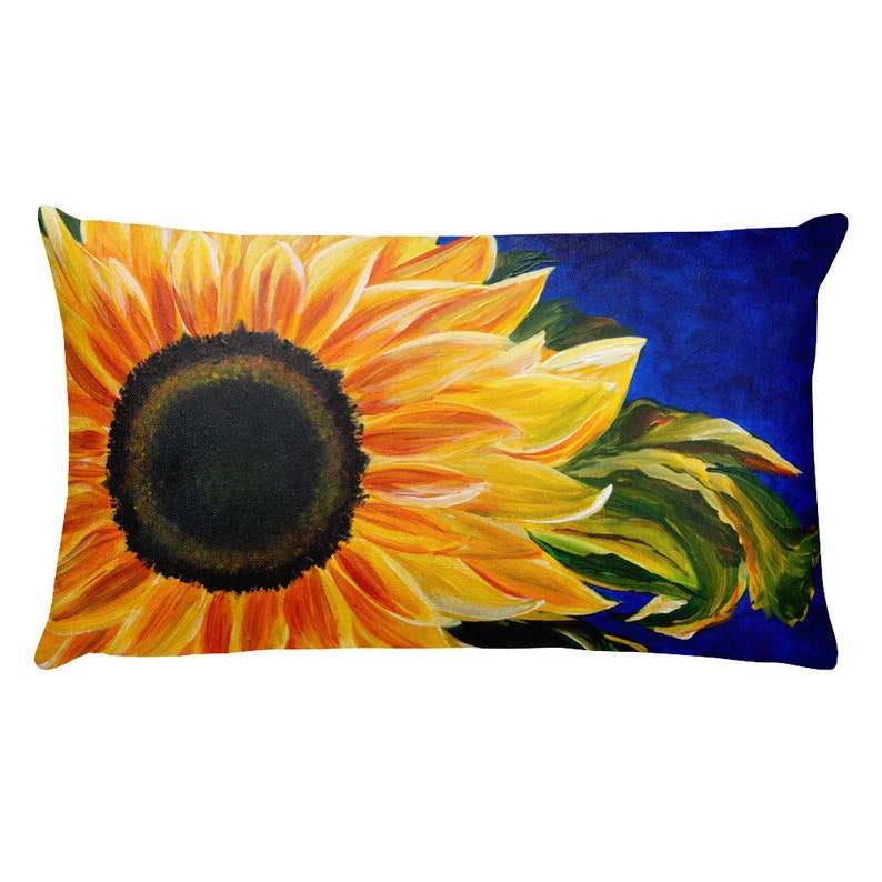 May include: A throw pillow with a painting of a sunflower with yellow petals and a dark brown center. The background is a deep blue color.