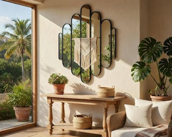 Puede incluir: Un espejo de pared decorativo con un marco de metal negro y múltiples espejos ovalados. Un tapiz de macramé cuelga frente al espejo. Una consola de madera con plantas en macetas y cestas de mimbre está frente a una ventana.