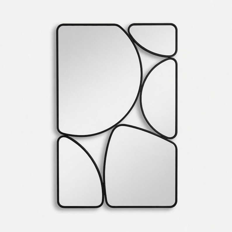 May include: A modern wall mirror with an abstract design. The mirror is composed of several irregularly shaped, reflective glass panels framed by a thin black metal border. The overall shape is rectangular, with the individual panels creating a unique, artistic look.