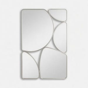 May include: A modern wall mirror with an abstract design. The mirror is composed of several irregularly shaped, rounded rectangles and semi-circles, all framed in a thin, silver-colored metal. The reflective surfaces are bright and clean, creating a contemporary aesthetic.
