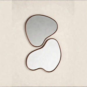 May include: Two wall mirrors with irregular, organic, amoeba-like shapes. Each mirror features a thin, dark brown frame that follows the curved, non-symmetrical outline of the glass, creating a fluid and balanced visual composition.