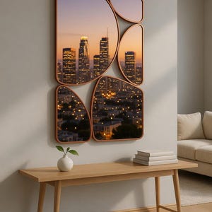 May include: A set of five copper-framed mirrors with an abstract design, each displaying a cityscape at dusk. The mirrors are mounted on a light gray wall above a wooden bench with a small white vase and books.