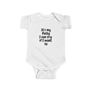 May include: White baby bodysuit with the text "It's my Potty I can cry if I want to" in black. The bodysuit is short-sleeved and has a snap closure at the bottom. The text is centered on the front of the garment.