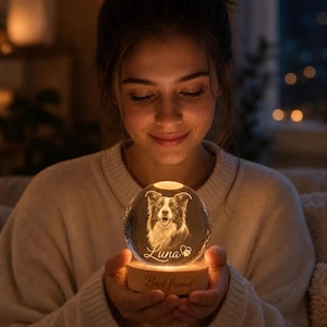 May include: A glowing glass sphere with a detailed etched portrait of a dog, resting on a wooden base. The base is inscribed with "Best friend" and the dog's name, "Luna". The sphere is lit from within, creating a warm, inviting glow.