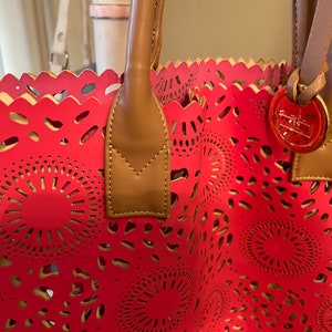Bolso Courage B vintage de piel rosa con diseños calados y asas superiores de piel color canela. 35,5 x 40,6 cm. Con medallón de latón. Forrado en rosa.