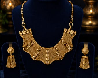 May include: A gold-toned jewelry set consisting of a wide, fan-shaped bib necklace with intricate wire-like detailing and geometric patterns, paired with matching drop earrings featuring a circular stud and a flared, textured pendant design.
