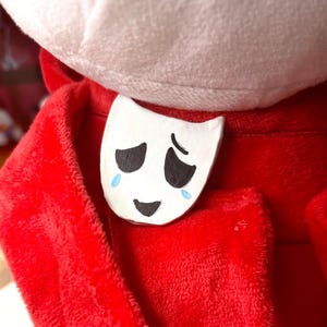 May include: A white ceramic mug with a black handle and the text "But First, Coffee" in a black, handwritten-style font. The mug is on a white surface.