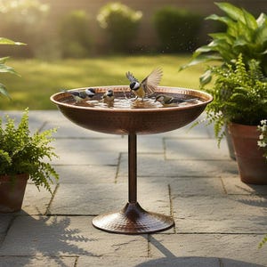 May include: A copper bird bath with a wide, shallow bowl and a pedestal base. Several small birds are bathing in the water, with one bird mid-flight. The bird bath is surrounded by potted plants and flowers, creating a serene outdoor scene.
