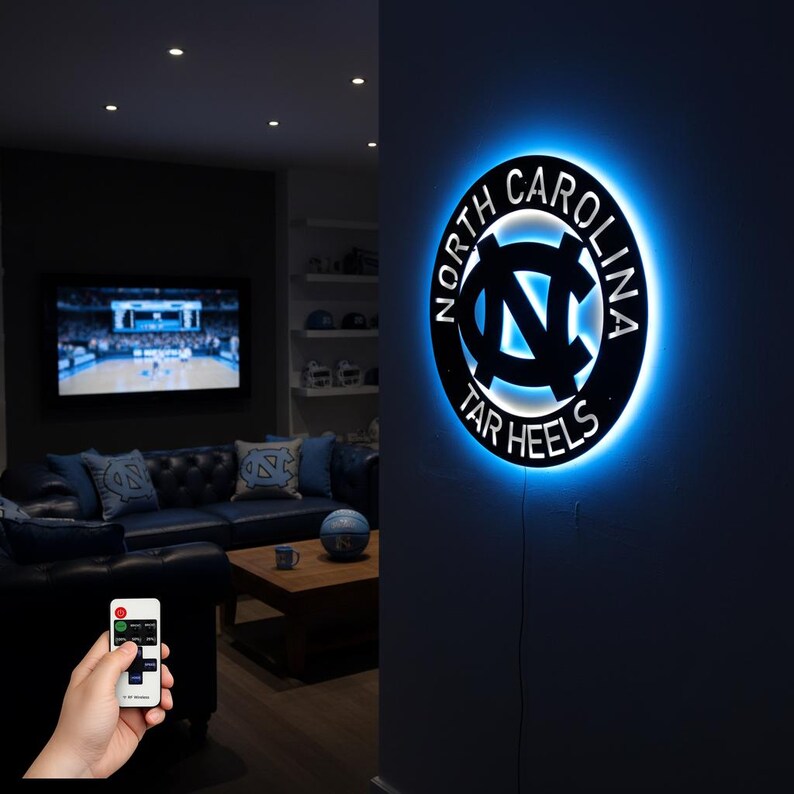 May include: A black and blue illuminated wall sign featuring the words "North Carolina Tar Heels" encircling the team's logo. The sign is lit with a blue glow, creating a striking visual effect. The sign is mounted on a dark wall.