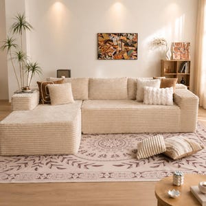 Puede incluir: Un sof&aacute; seccional de pana beige con varios cojines. El sof&aacute; est&aacute; colocado sobre una alfombra estampada. Una peque&ntilde;a mesa auxiliar con una planta est&aacute; al lado del sof&aacute;. Una pintura cuelga de la pared.