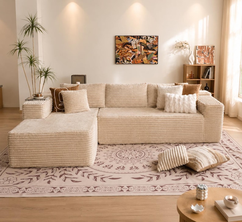 Puede incluir: Un sof&aacute; seccional de pana beige con varios cojines. El sof&aacute; est&aacute; colocado sobre una alfombra estampada. Una peque&ntilde;a mesa auxiliar con una planta est&aacute; al lado del sof&aacute;. Una pintura cuelga de la pared.